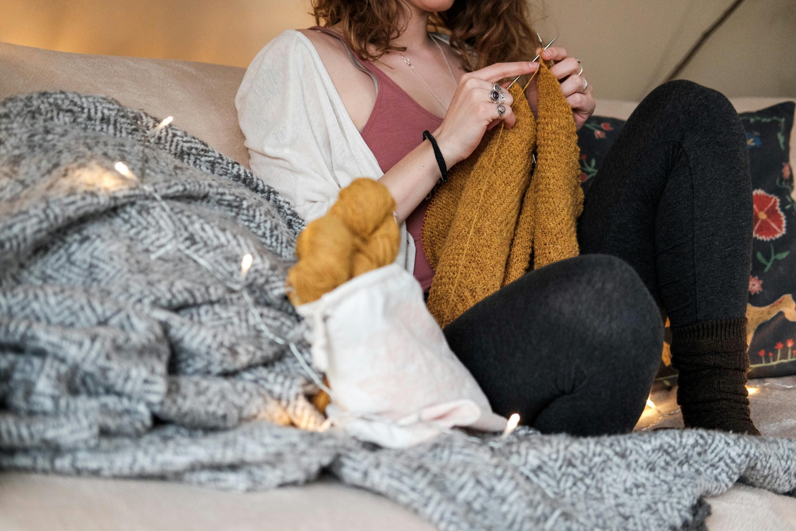Woman knitting a mustard colored garment.